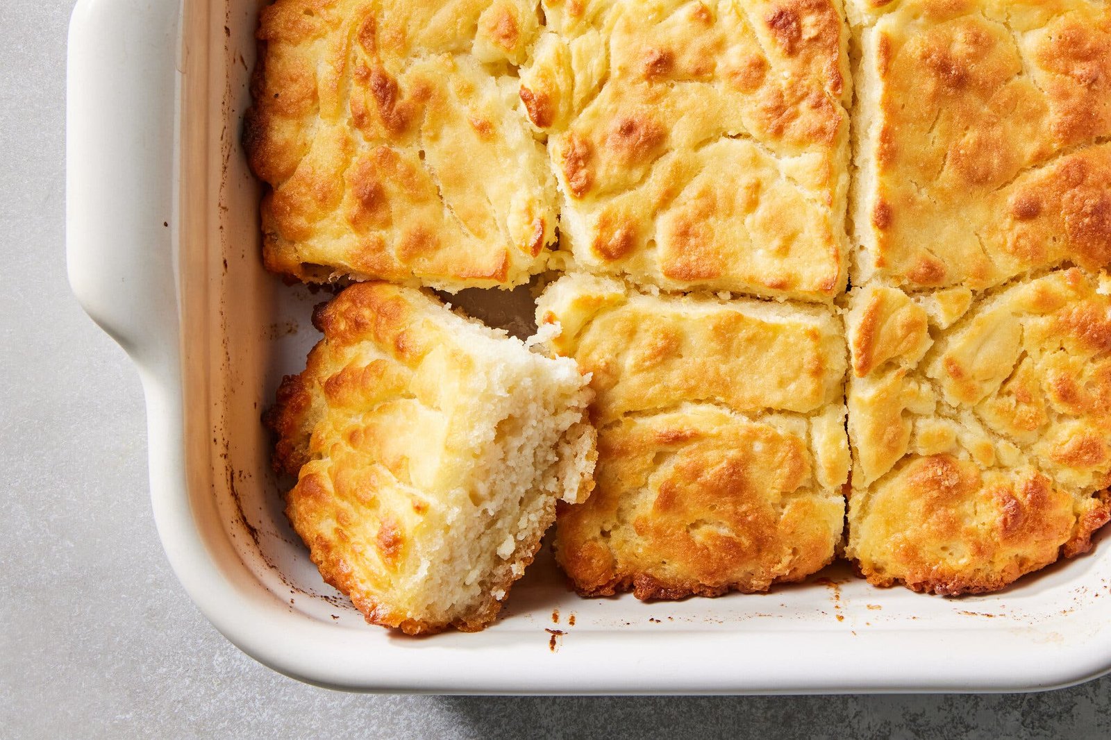 Square biscuits are cut directly in a white baking dish.