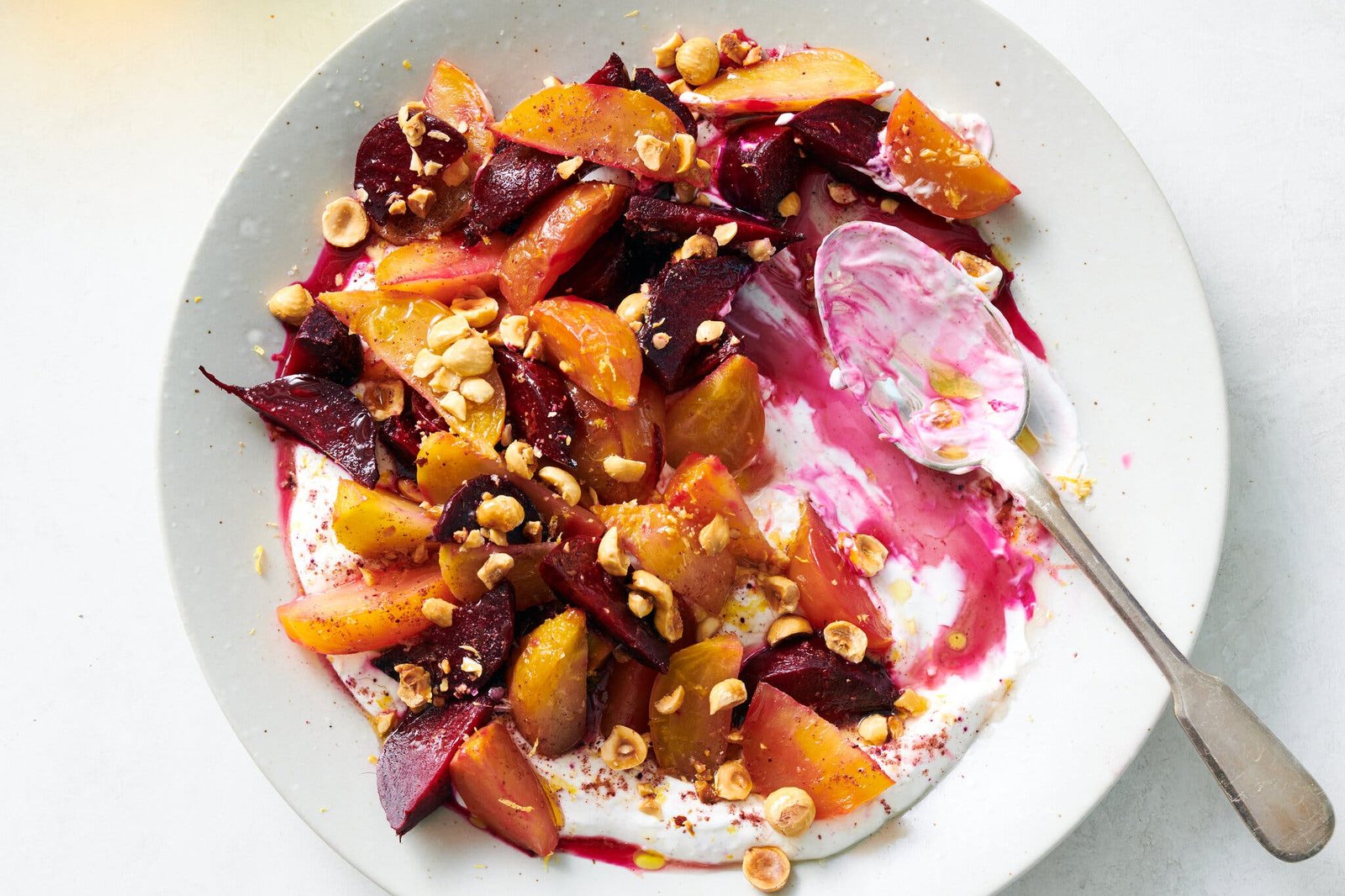 Yogurt, roasted beets and hazelnuts are layered into a white dish.