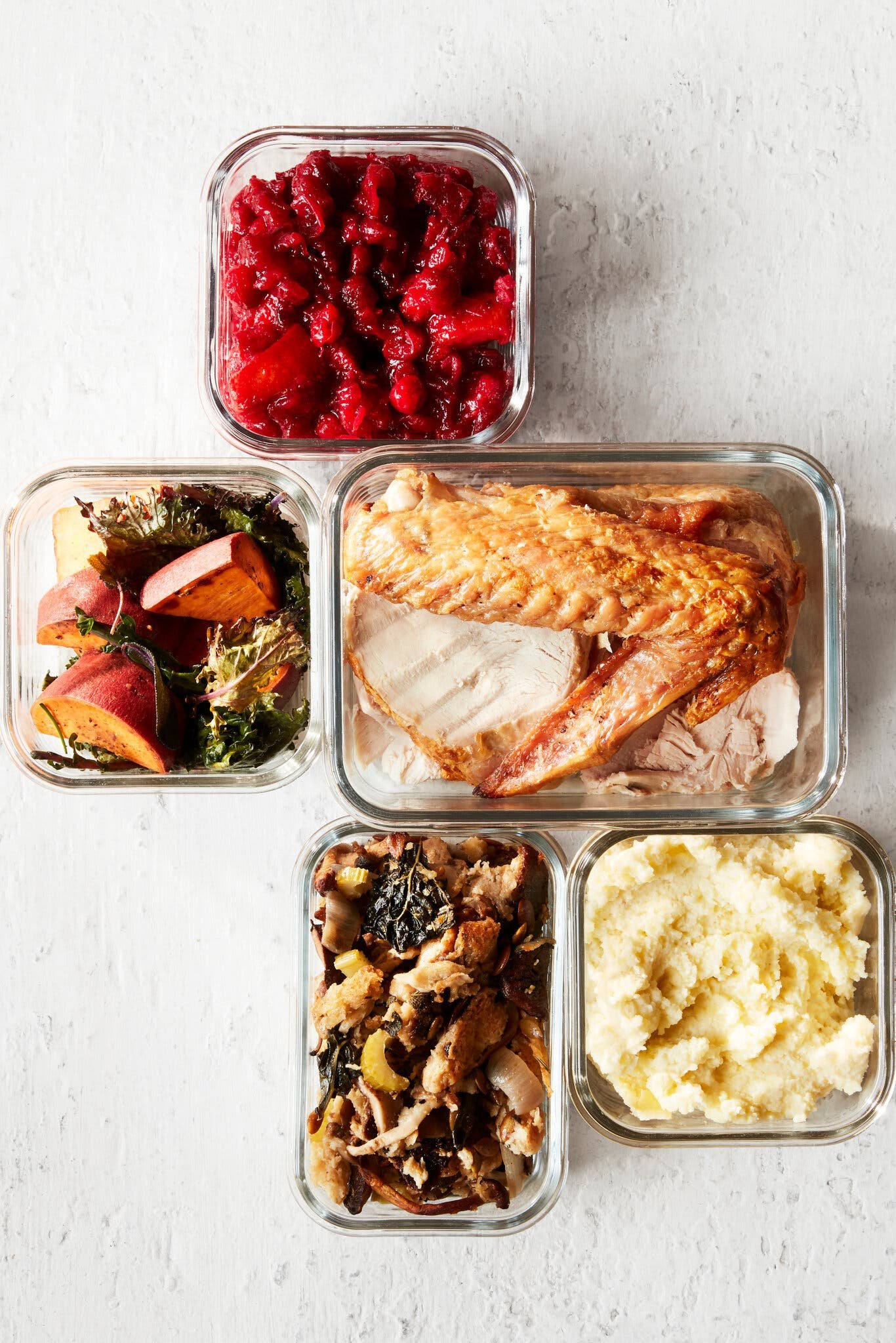 An overhead image of five glass containers filled with various Thanksgiving foods.