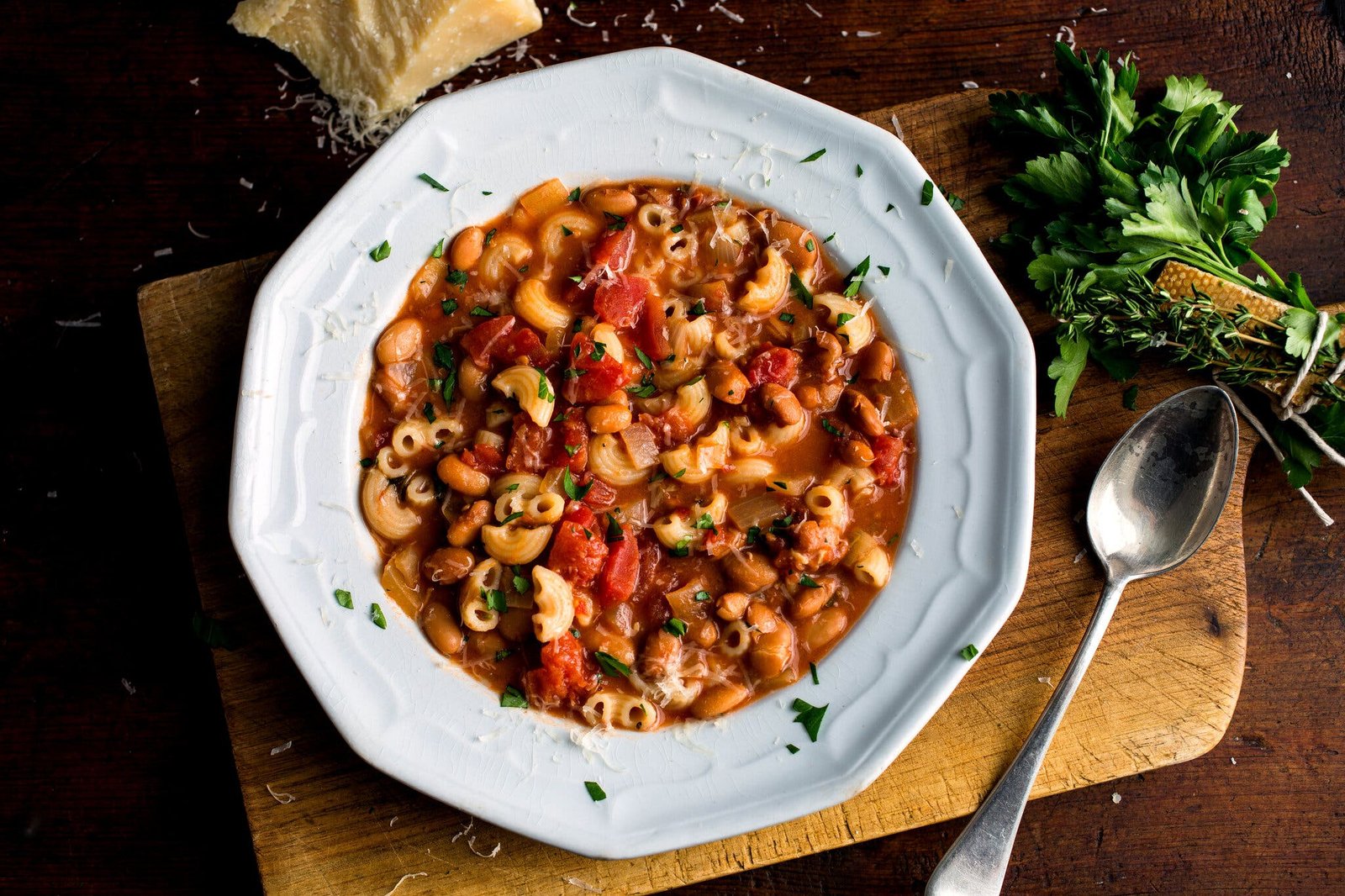 An overhead image of a wide-rimmed bowl holding pasta e fagioli, full of macaroni and beans.