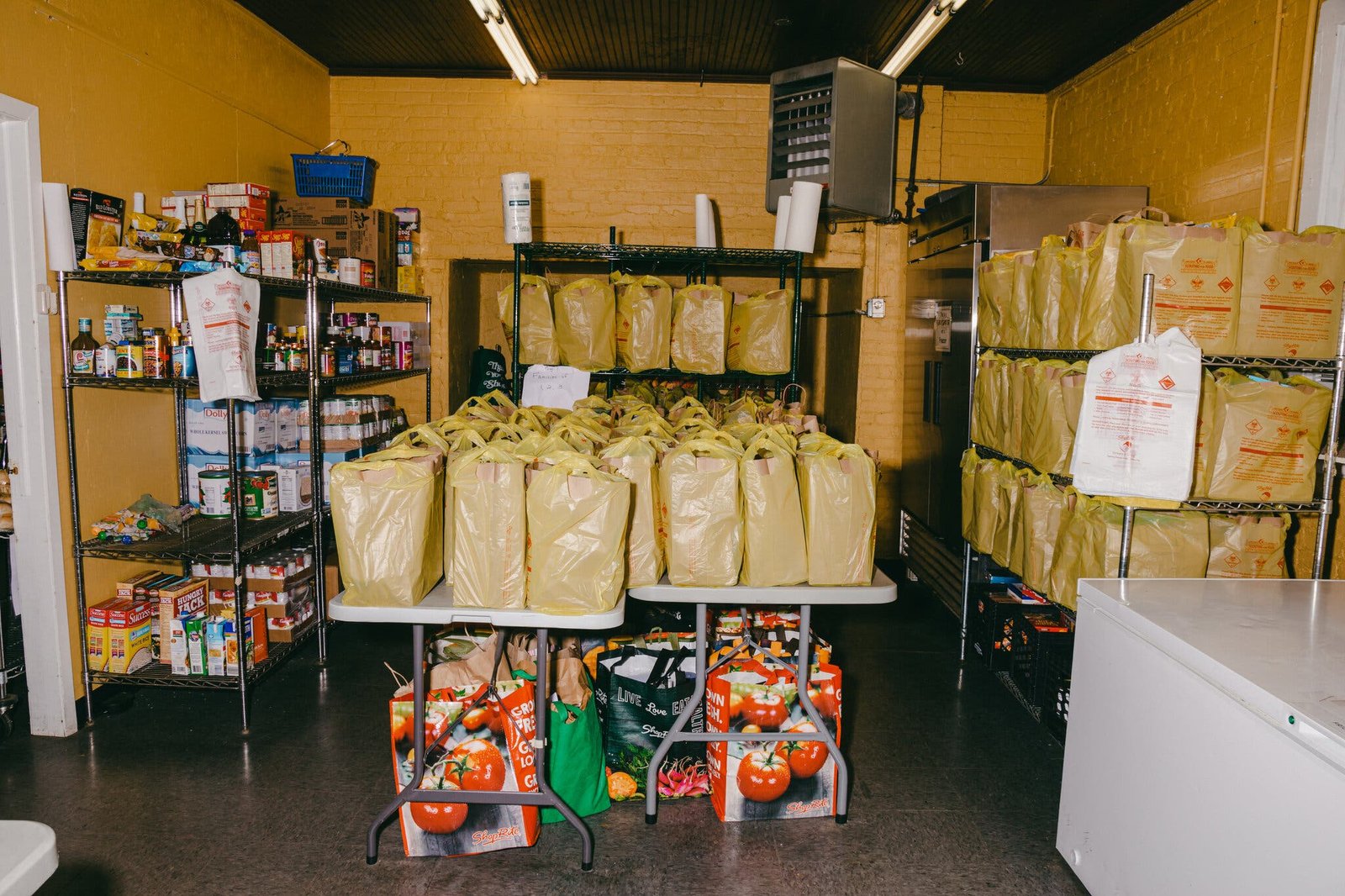 A side image of a food pantry with many grocery bags lined on a table and on shelves.