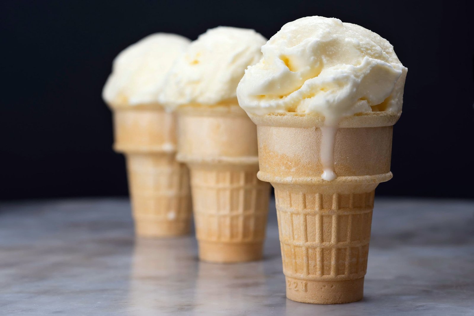 A side image of three cones of vanilla ice cream.