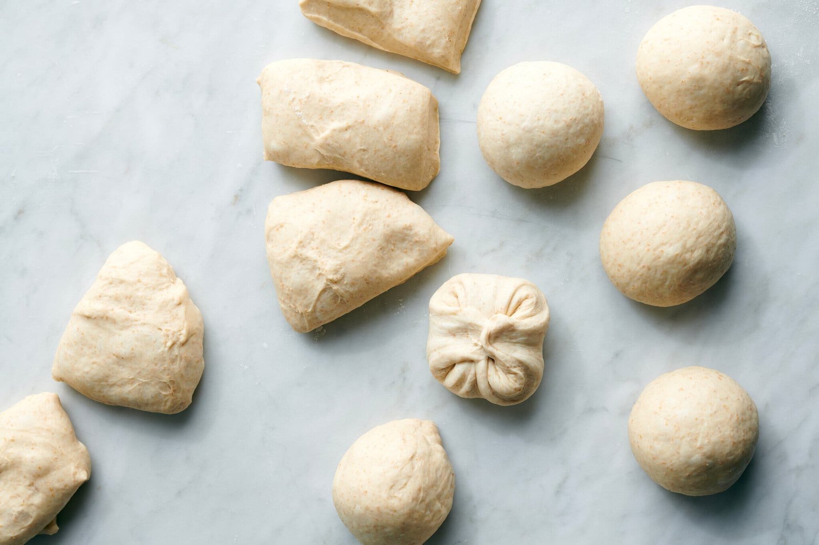 An overhead image of bagel dough cut into pieces, and some shaped into rounds.