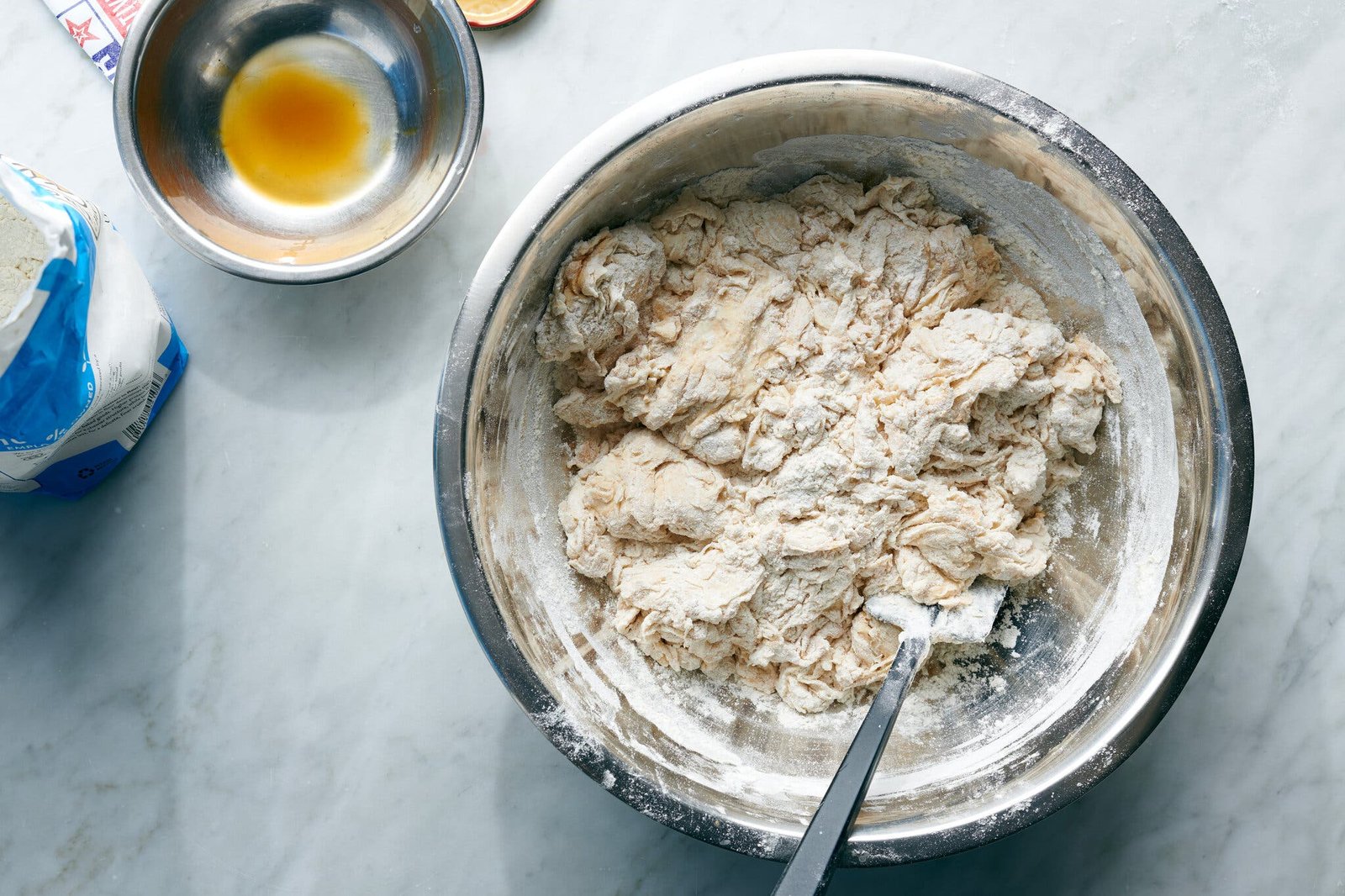 An overhead image of a shaggy dough in a steel bowl.