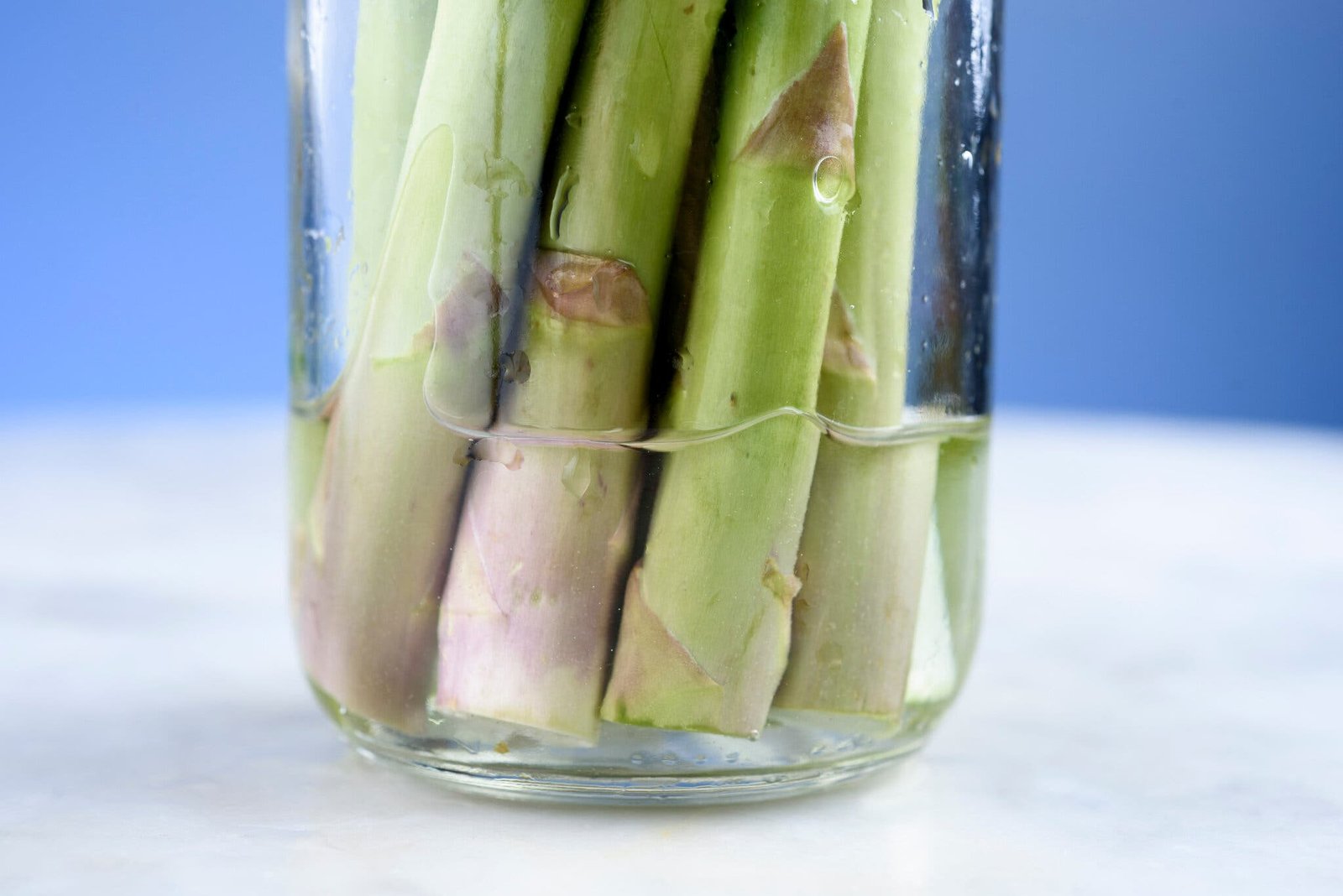 A side image of asparagus stored in water in a jar.