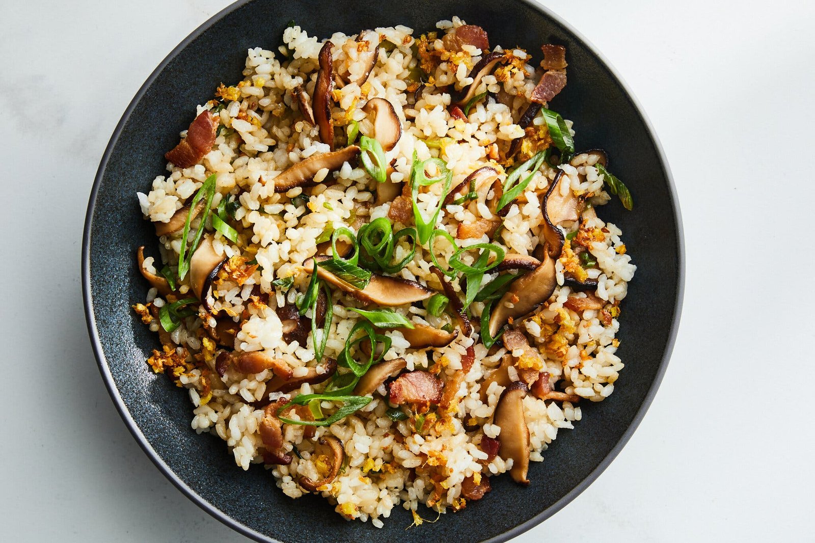 An overhead image of mushroom studded rice topped with sliced scallions.