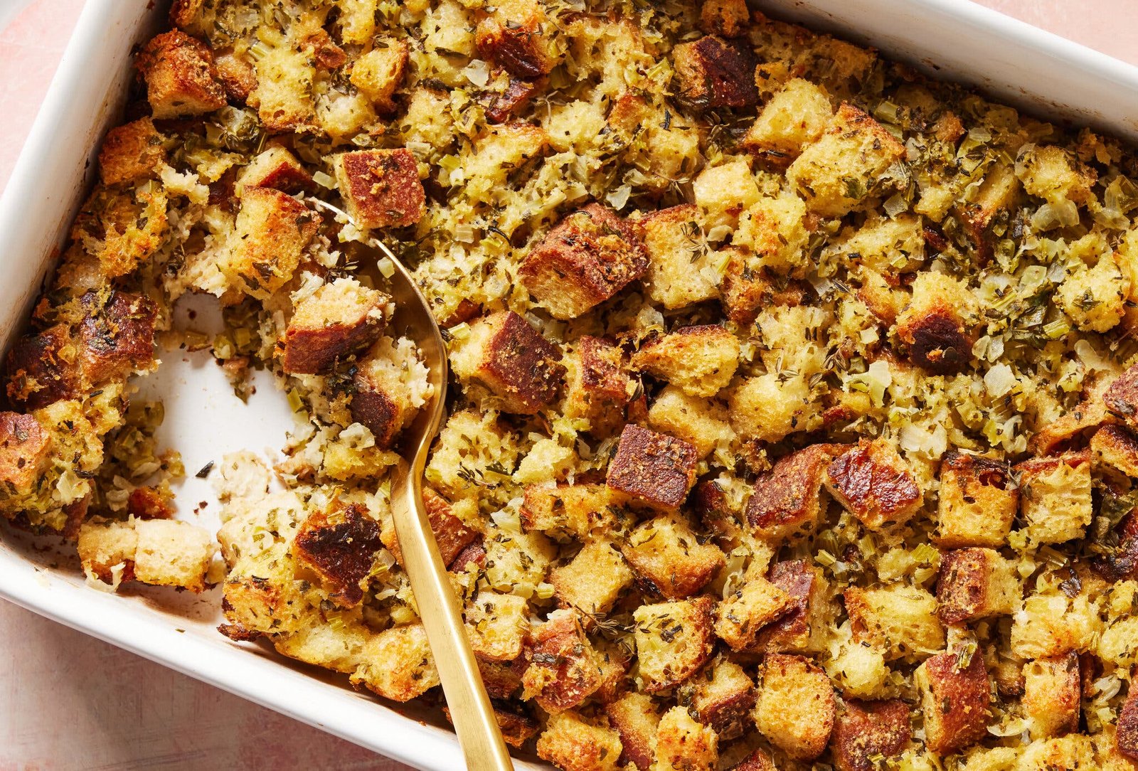 An overhead image of stuffing in a baking dish with a scoop taken out.