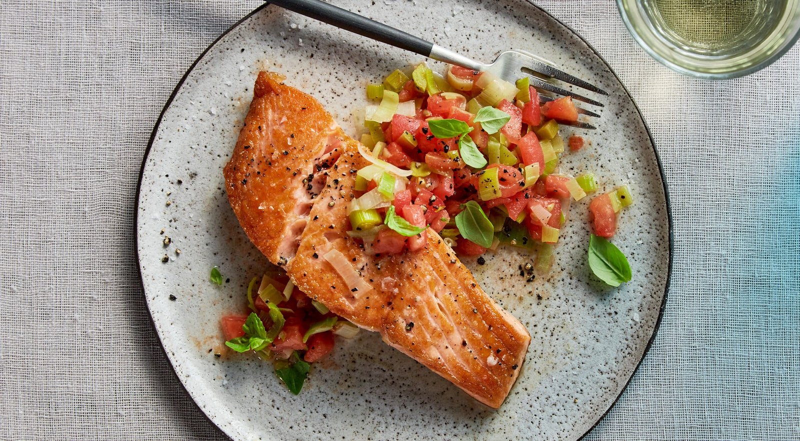 An overhead image of sauteed salmon next to a leek and tomato salad.