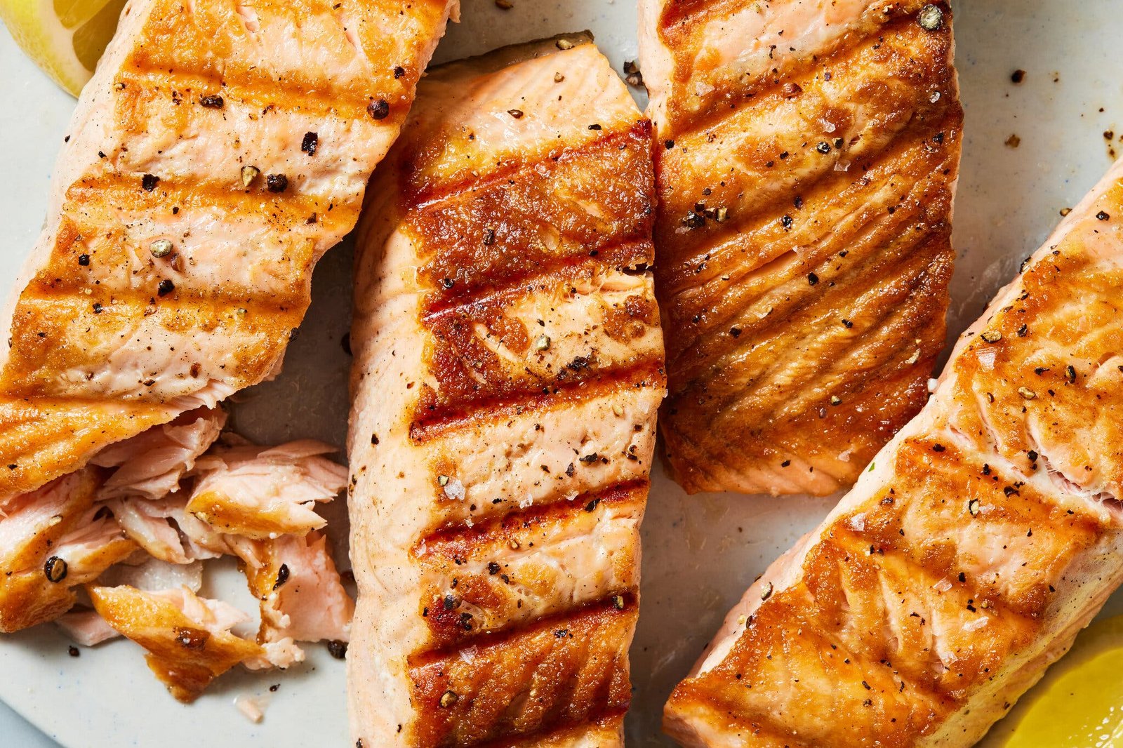 An overhead image of four salmon fillets with grill marks on top.
