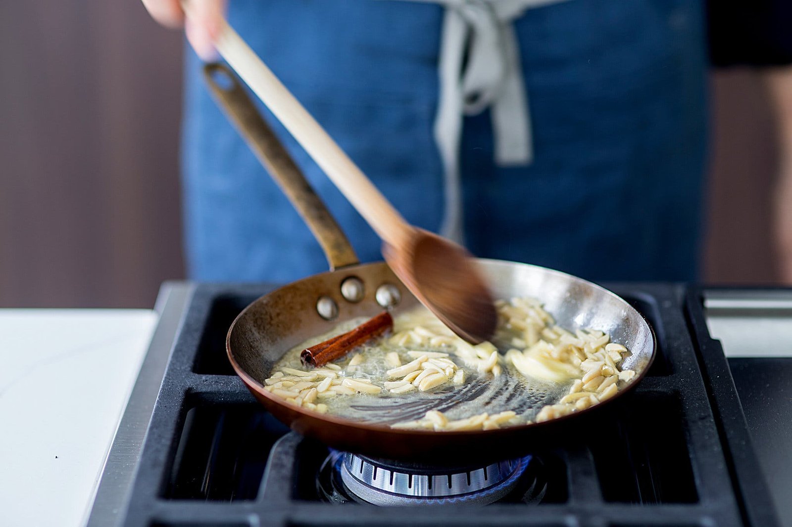 A side image of nuts and a cinnamon stick being toasted in butter.