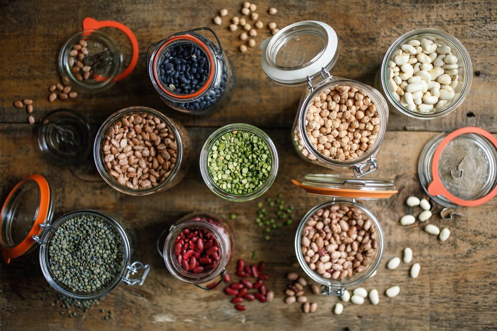 An overhead image of various kinds of beans in jars.