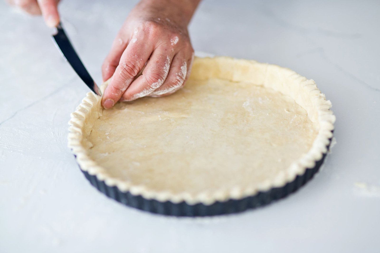 A side image of raw pie dough being tucked into a pie dish.