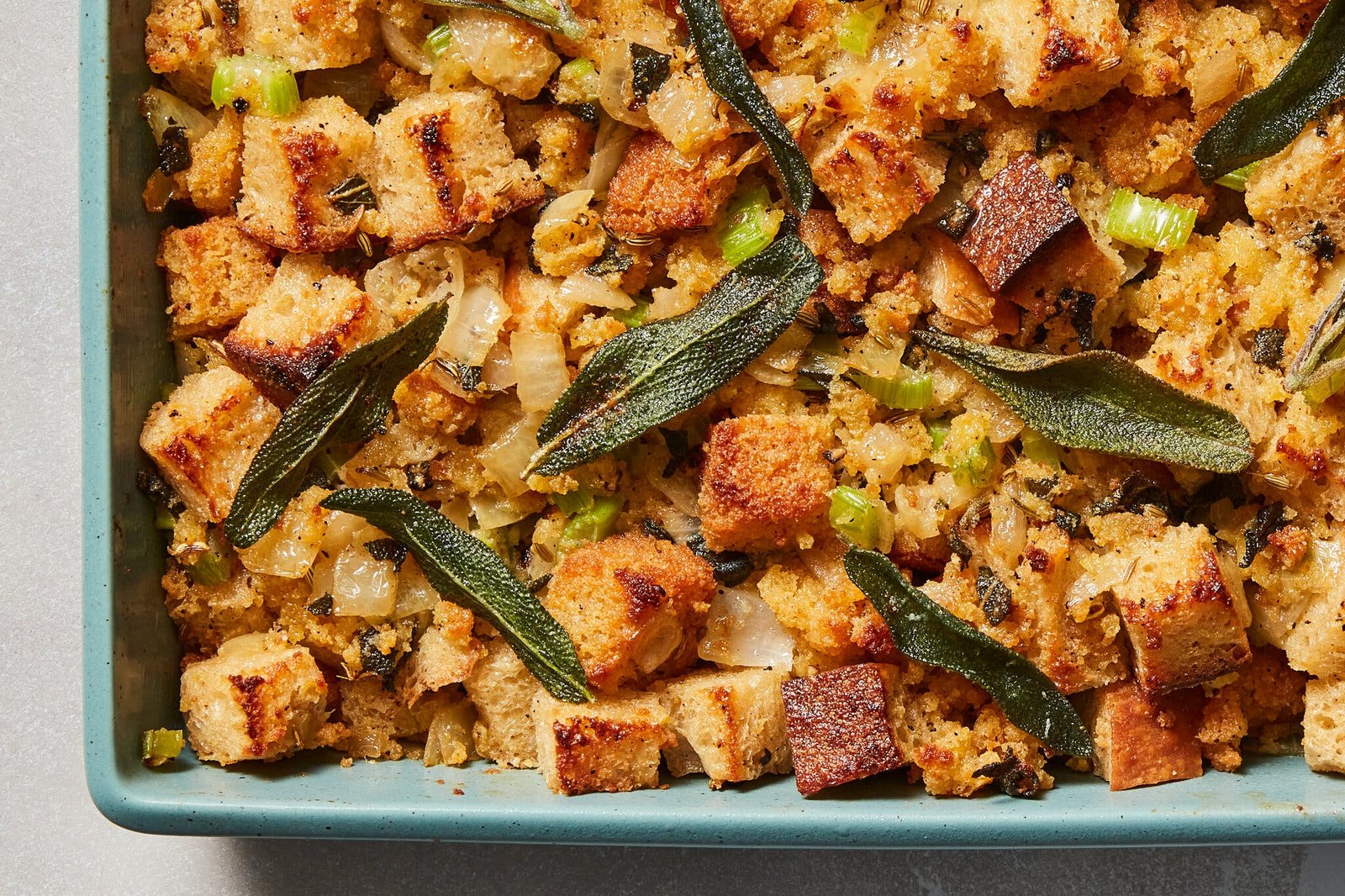 A casserole dish holds Thanksgiving stuffing topped with fried sage leaves.