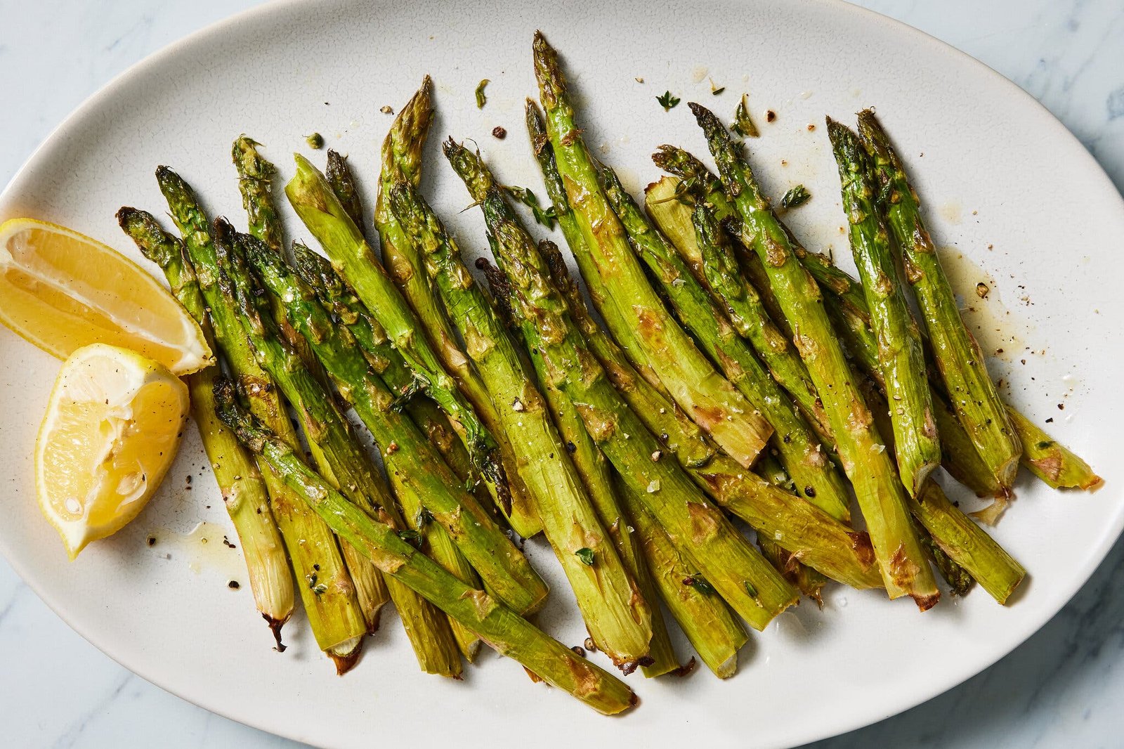 An overhead image of roasted asparagus on a white platter.