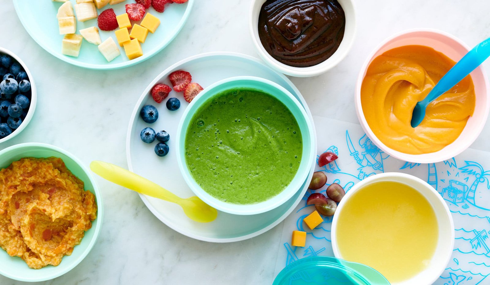 An overhead image of multiple colorful bowls filled with baby food.