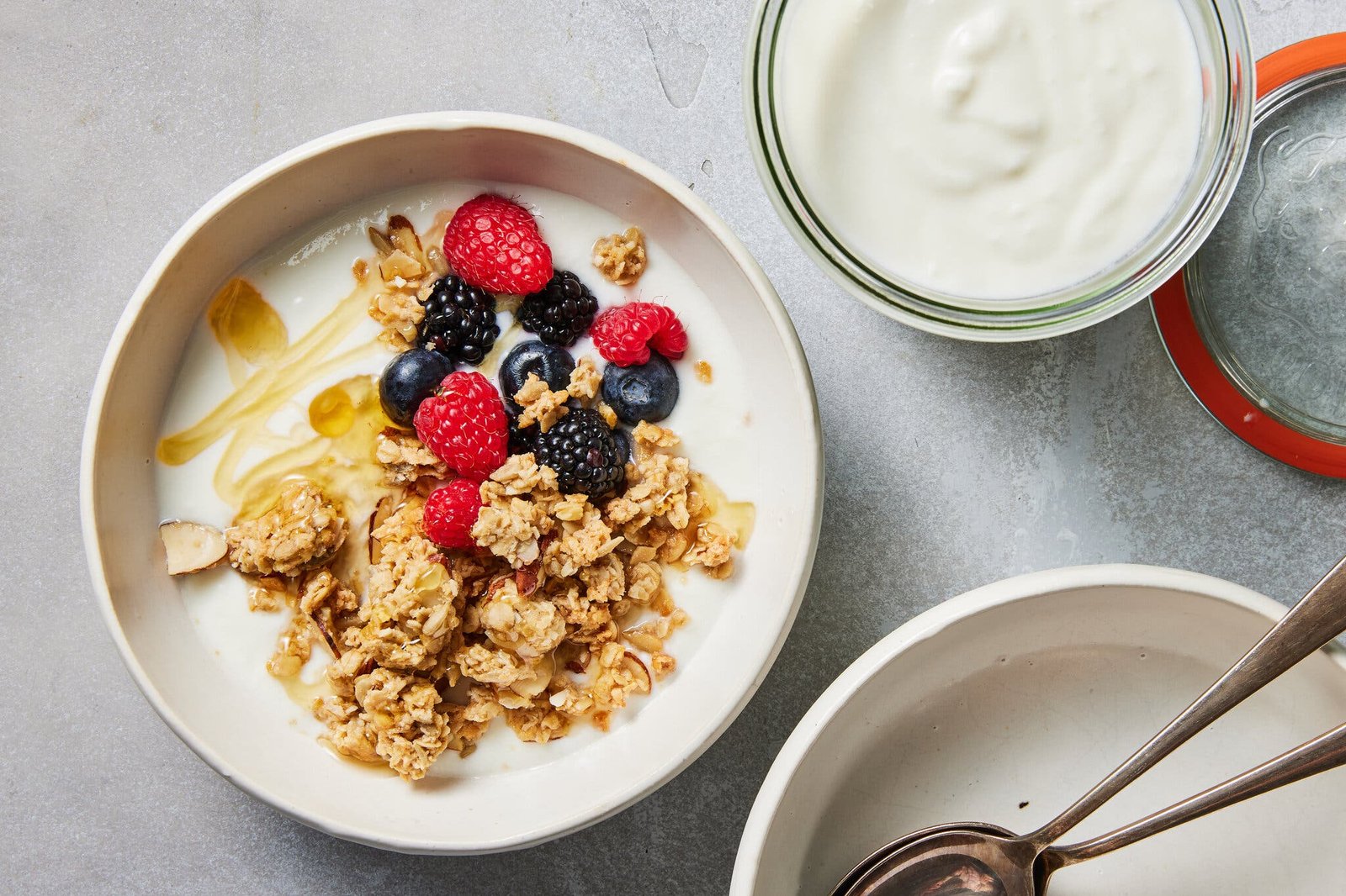An overhead image of a bowl of yogurt topped with granola, fruit and honey.