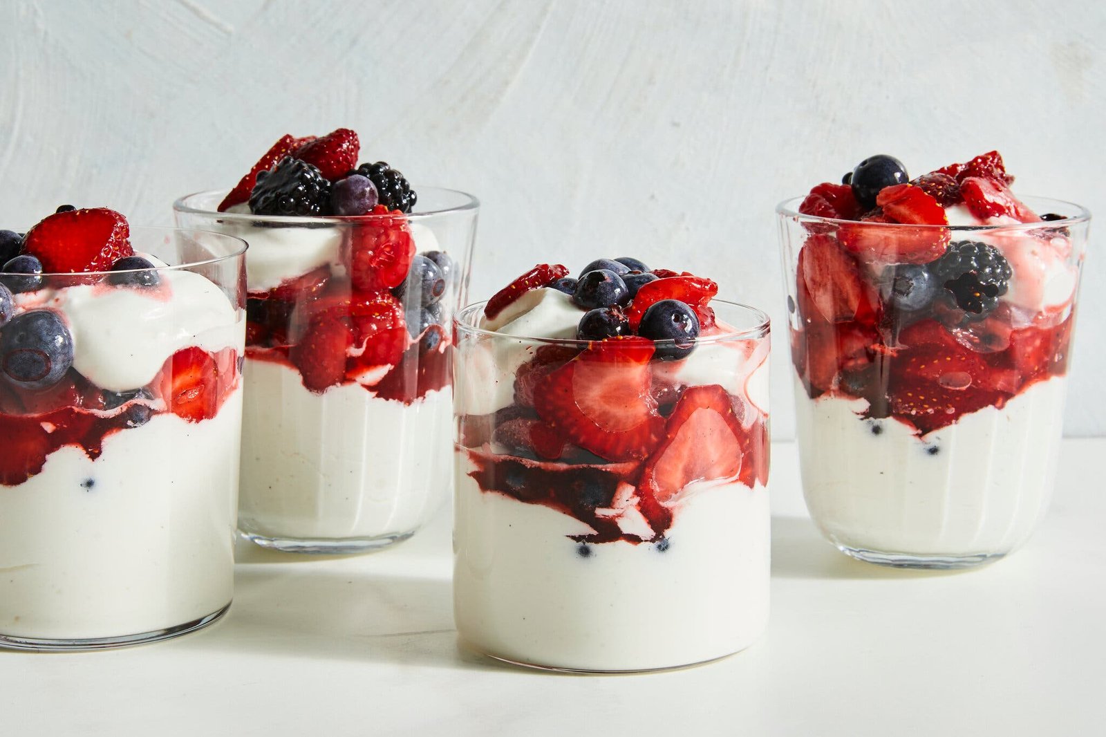 A side image of four cups of yogurt topped with fruit.