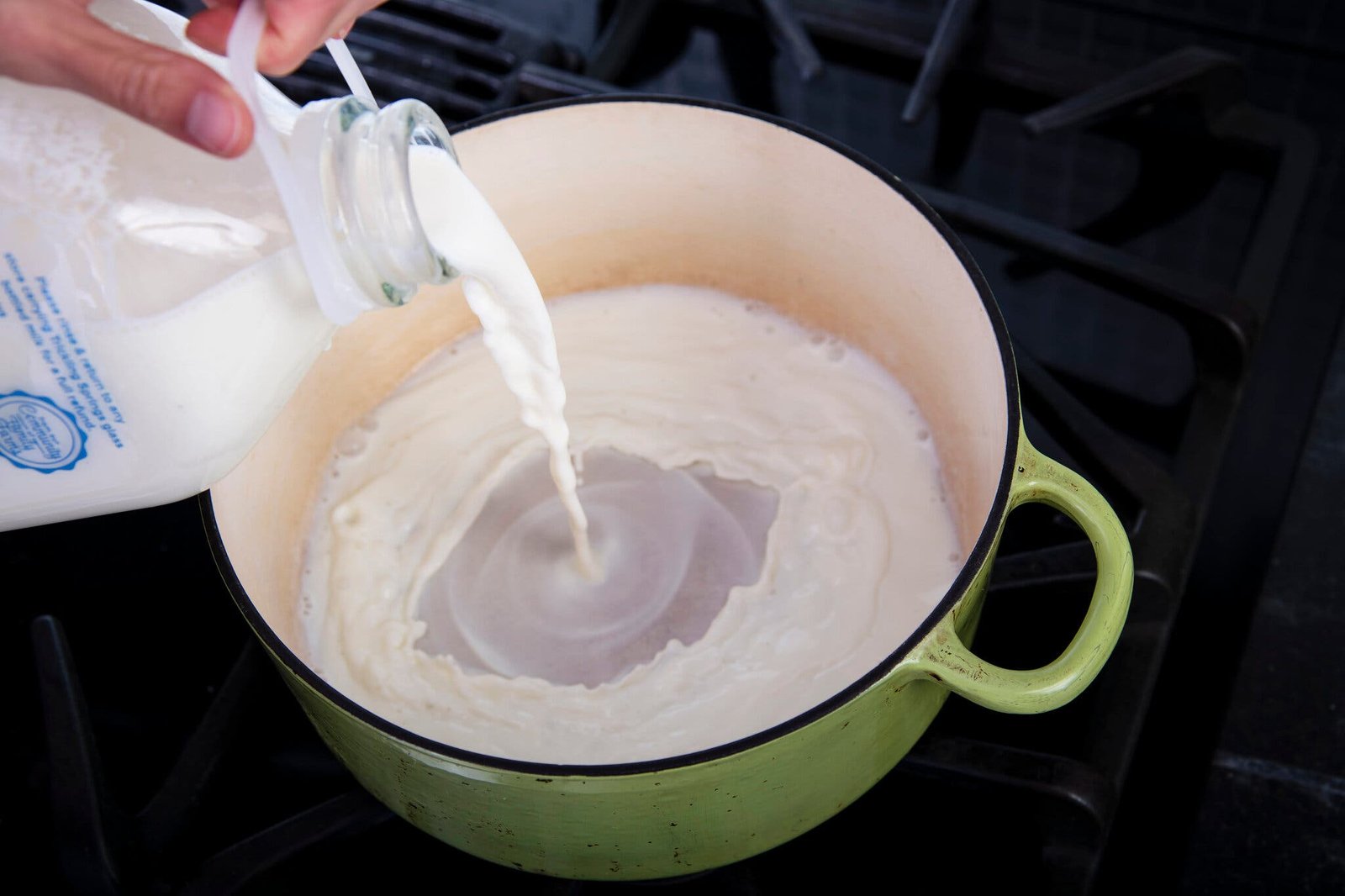 An overhead image of milk being poured into a Dutch oven.