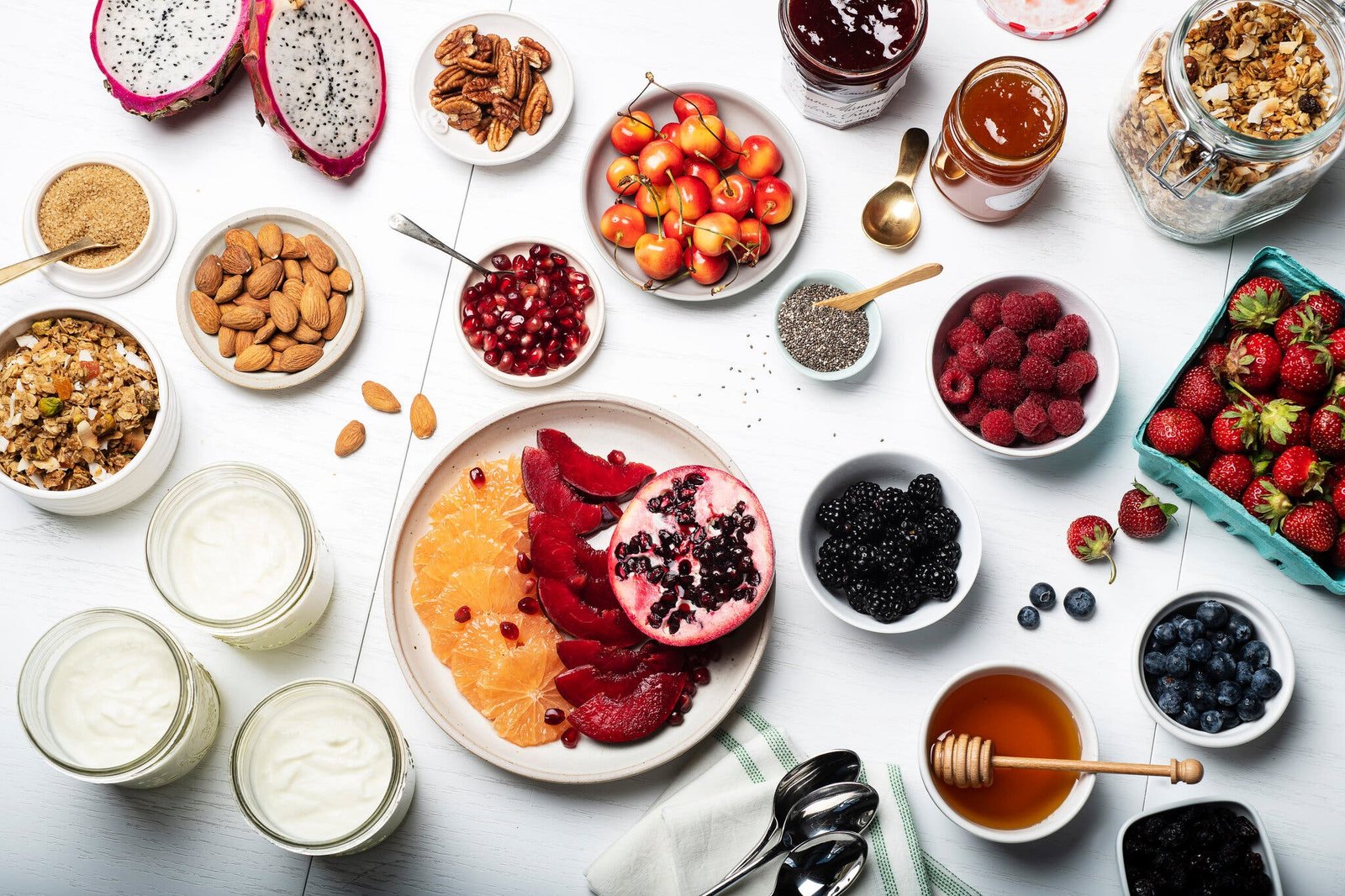 An overhead image of yogurt toppings, including nuts, berries, seeds and granola.