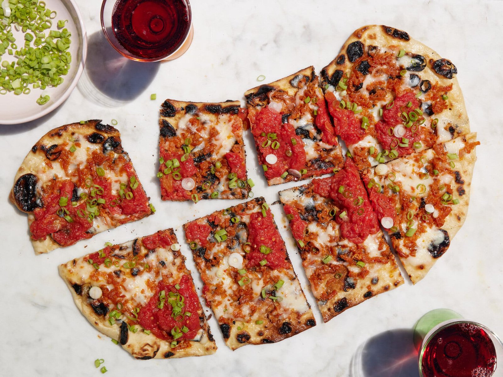 An overhead image of a grilled pizza cut into eight pieces.