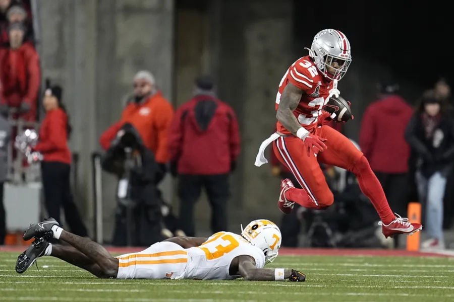 Dec 21, 2024; Columbus, Ohio, USA; Ohio State Buckeyes running back TreVeyon Henderson (32) hurdles Tennessee Volunteers quarterback Gaston Moore (13) during the first half of a College Football Playoff first round game at Ohio Stadium. Mandatory Credit: Adam Cairns-Imagn Images