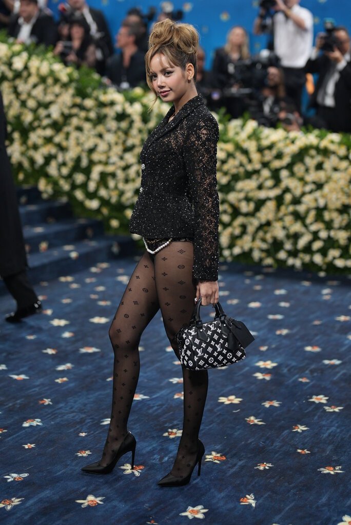 Lisa is wearing patterned tights, a bodysuit and a jeweled black jacket.