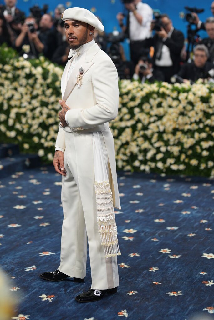 Lewis Hamilton wearing a cream suit and beret.