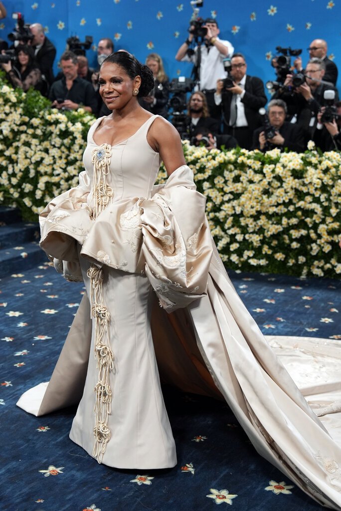 Audra Mcdonald wearing a beige gown with embellished flowers down the front and a voluminous peplum waistline.