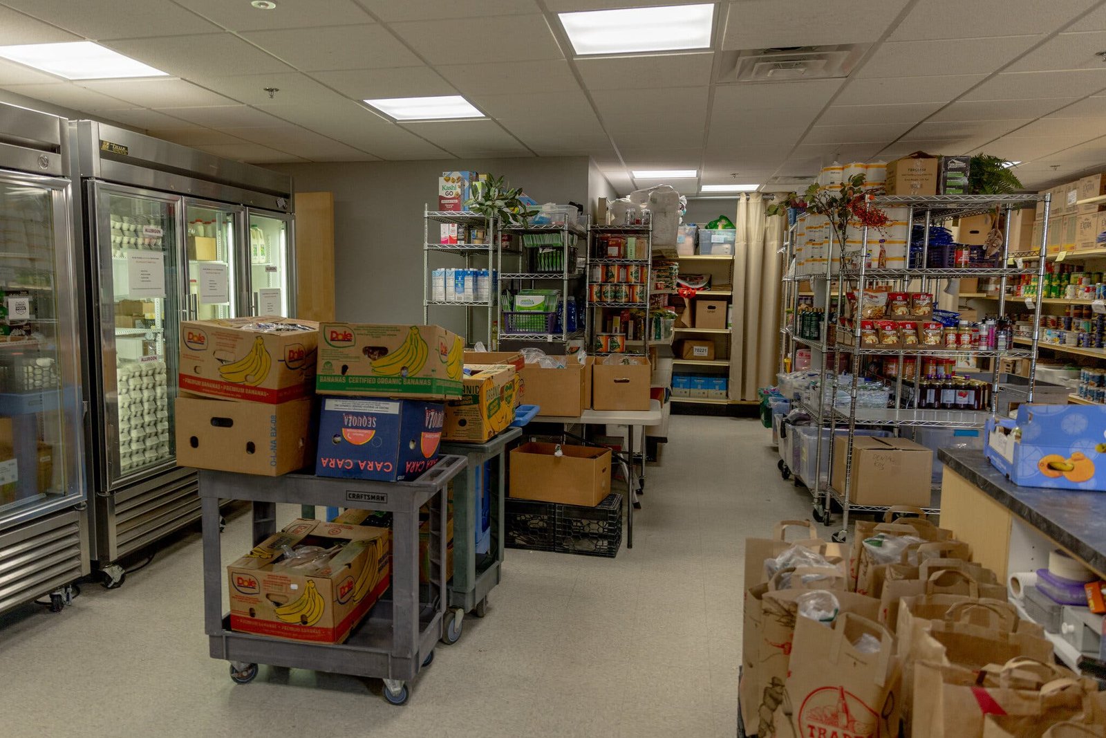 An image showing a room filled with silver racks and refrigerators stocked with food.